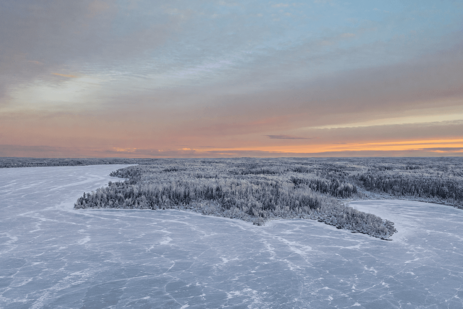 Aerial drone shot of Lac la Biche lake shoreline with forest and blue sky.